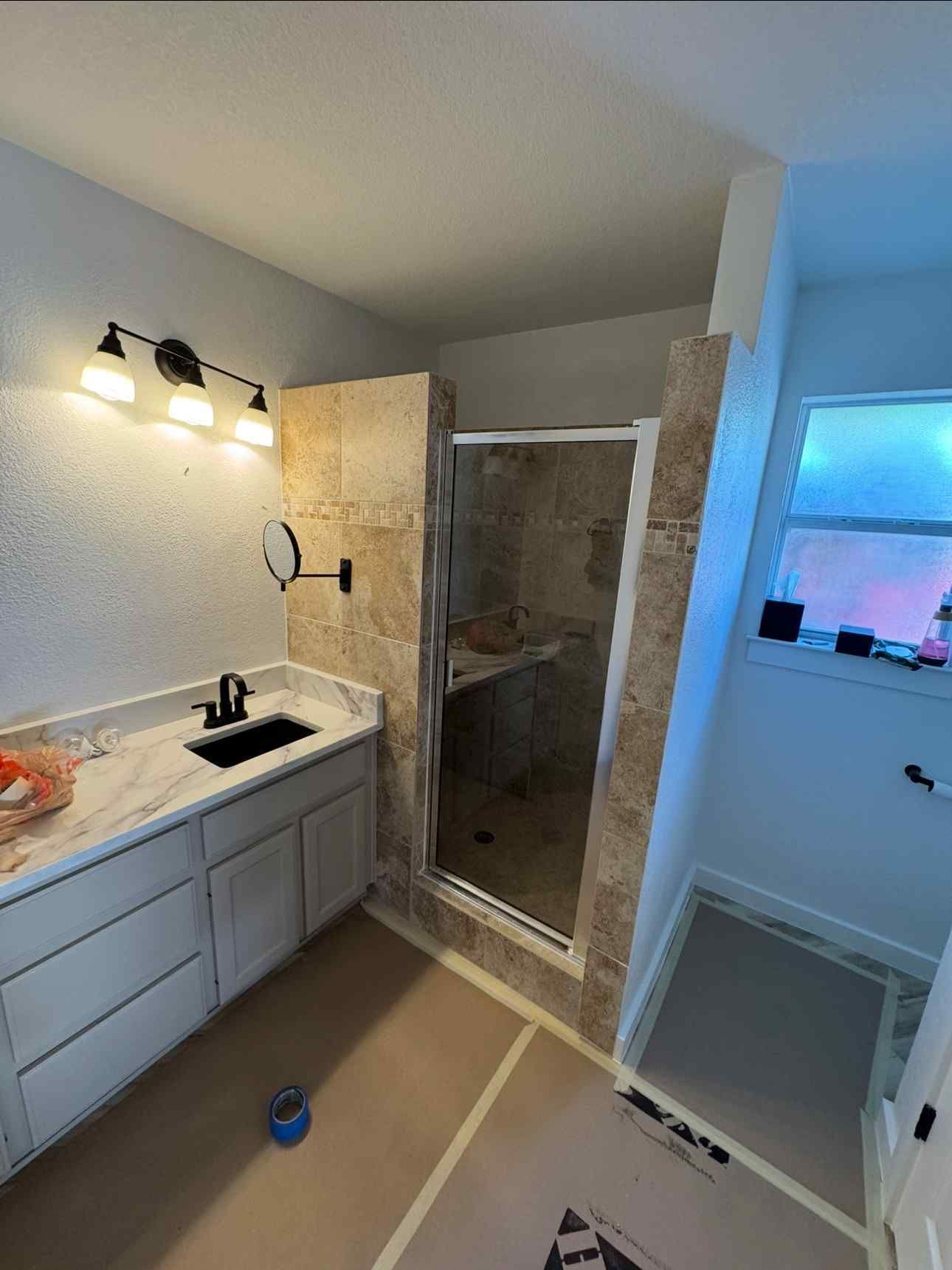 Bathroom with double vanity, lit mirror, shower stall, and built-in shelving alcove.