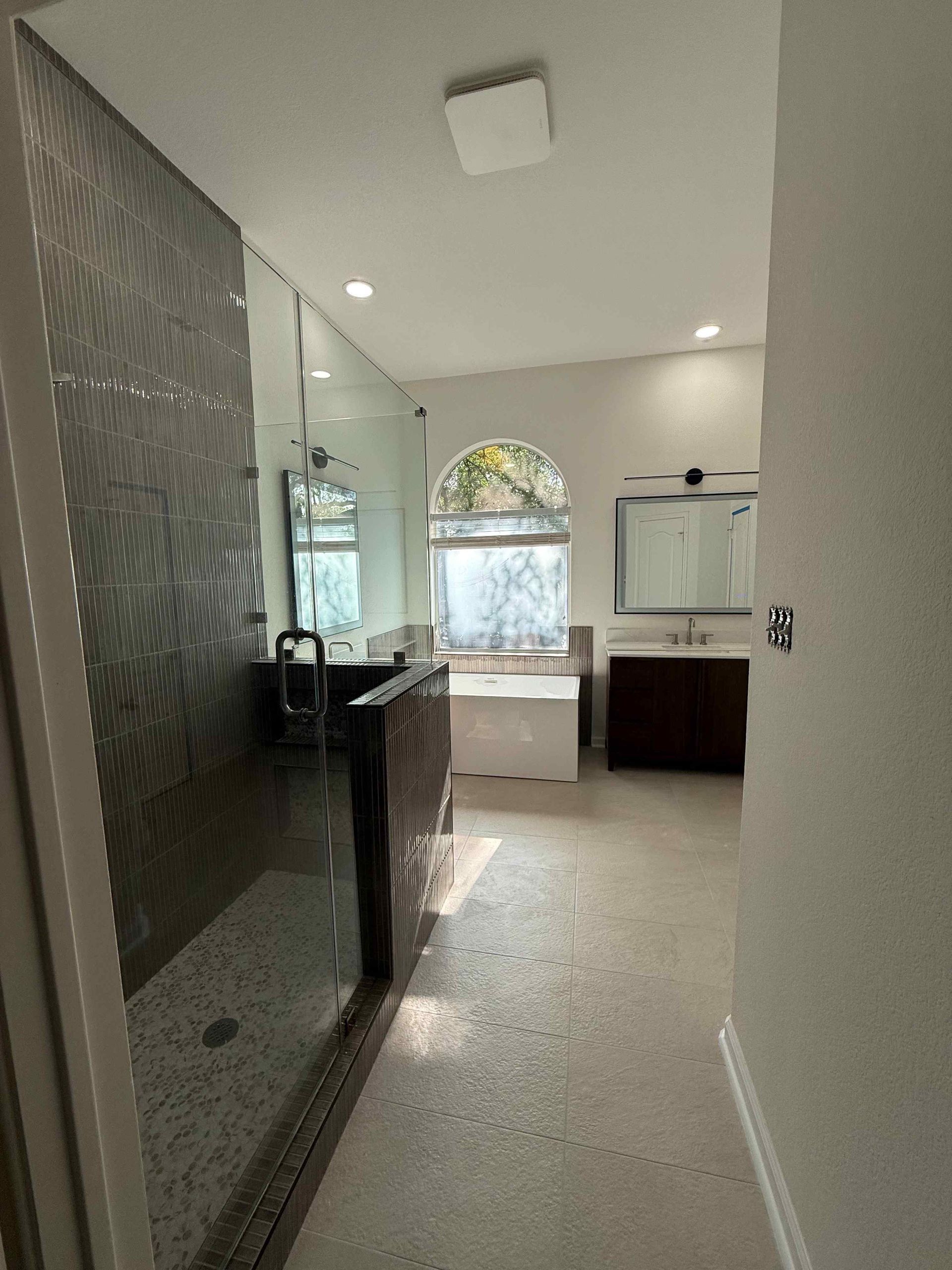 Modern kitchen with dark cabinets, white tile floor, and arched window by the sink