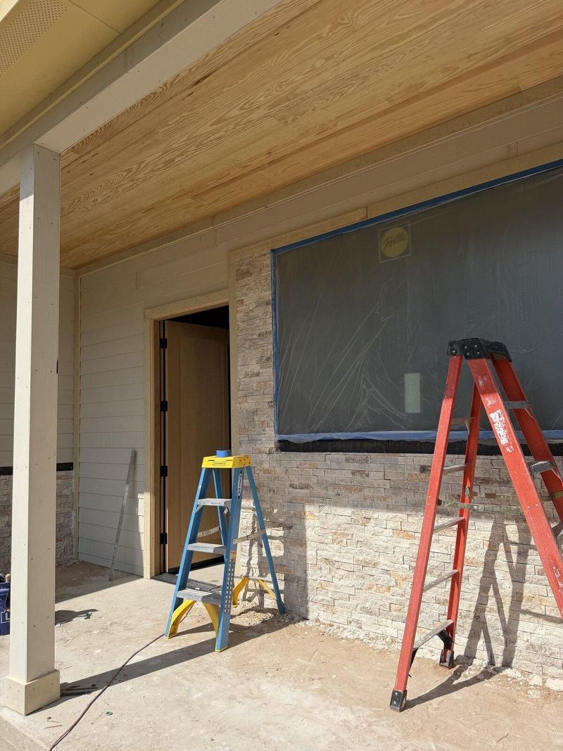 Covered porch under construction with stone column base and wood ceiling