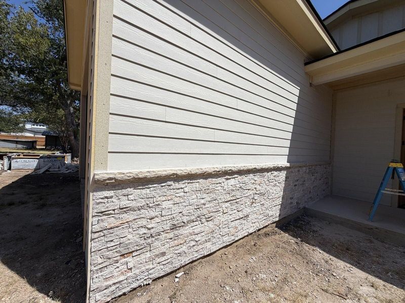 Completed exterior corner with lap siding above a stone base