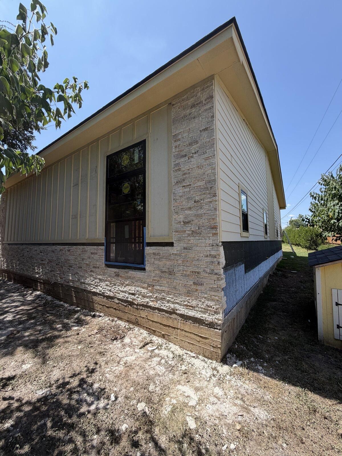 Completed exterior with board-and-batten siding and stone base