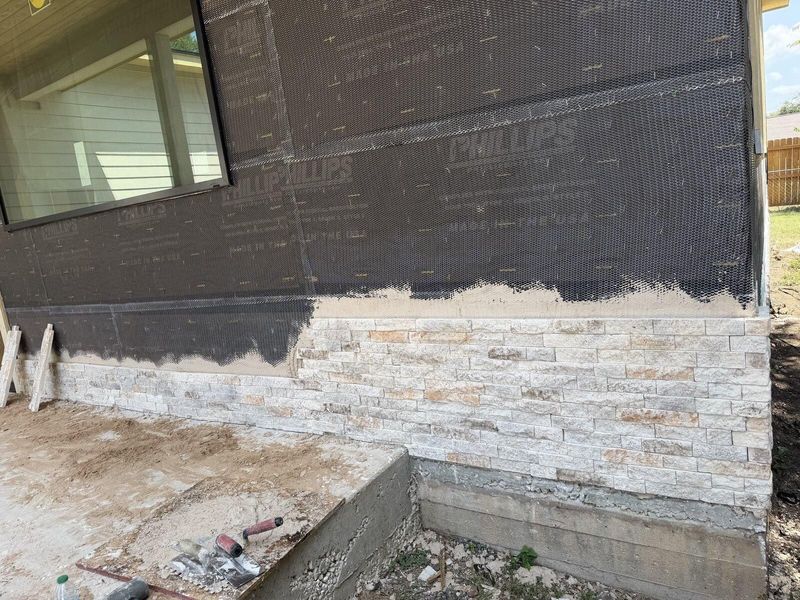 Stone veneer being installed over house wrap during an exterior home renovation
