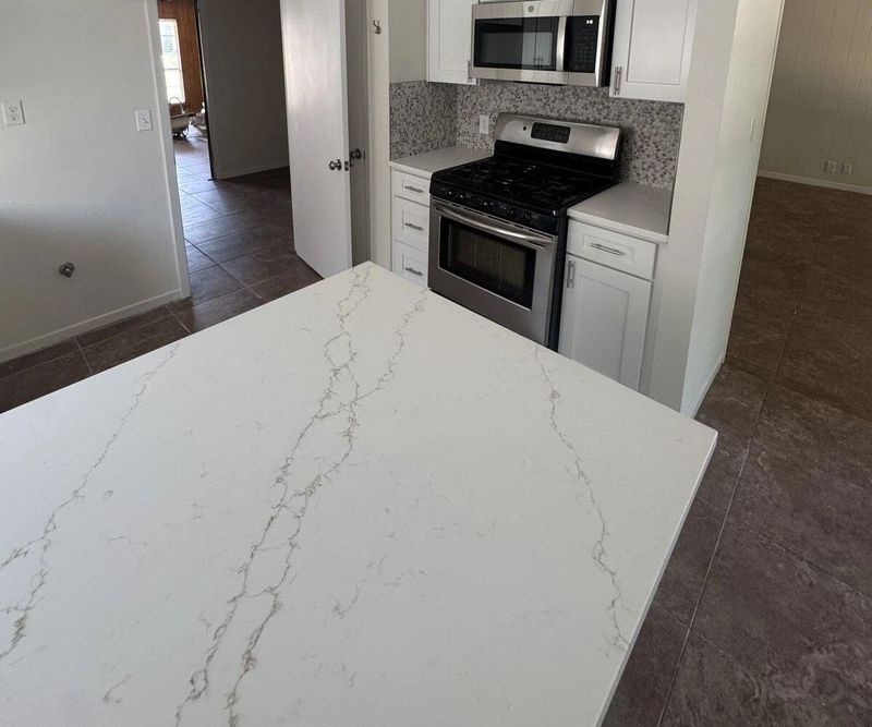 Remodeled kitchen with white cabinetry, quartz counters, and stainless appliances