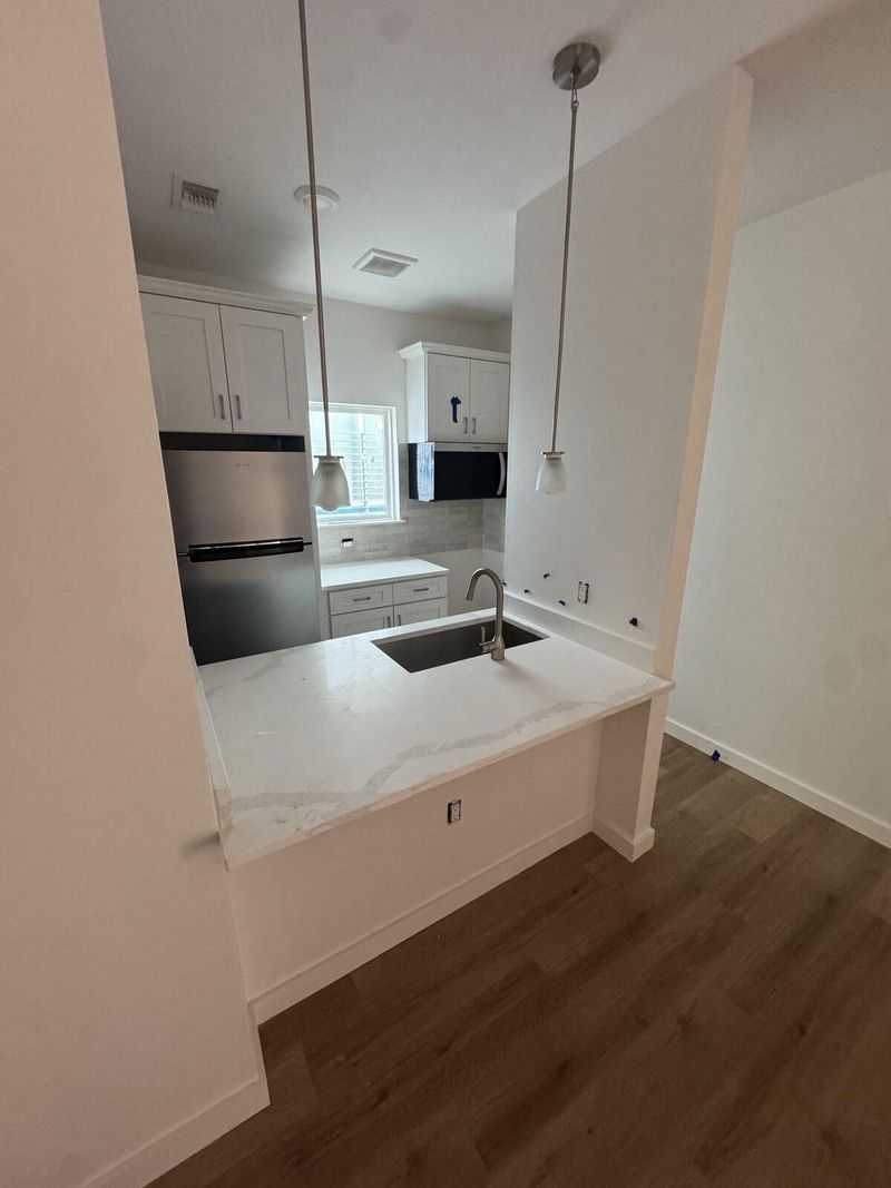 Remodeled kitchen with white shaker cabinets and a quartz peninsula