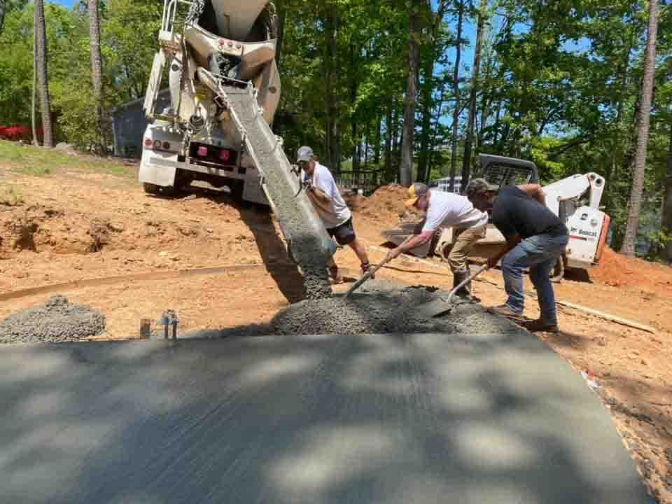 Workers paving a road with fresh asphalt beside a truck on a dirt roadside