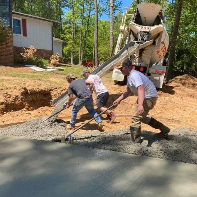 Construction workers paving a driveway as a cement truck pours fresh concrete at a house site