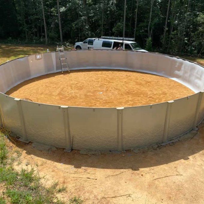 Round above-ground pool with muddy water and a ladder in a wooded yard, with a van behind it