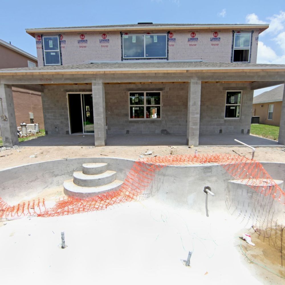 Partially built house with front porch and unfinished pool area in the foreground