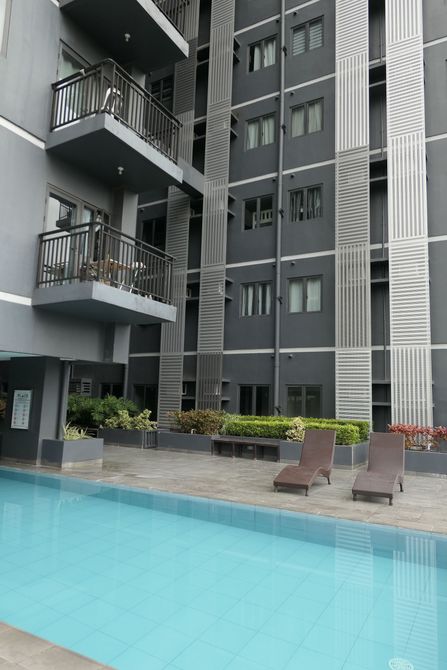 Apartment courtyard with turquoise pool, lounge chairs, and gray high-rise balconies.