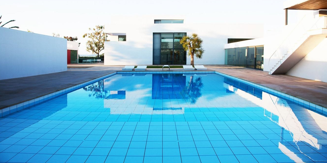 Bright blue swimming pool in a modern rooftop courtyard with white walls and stairs