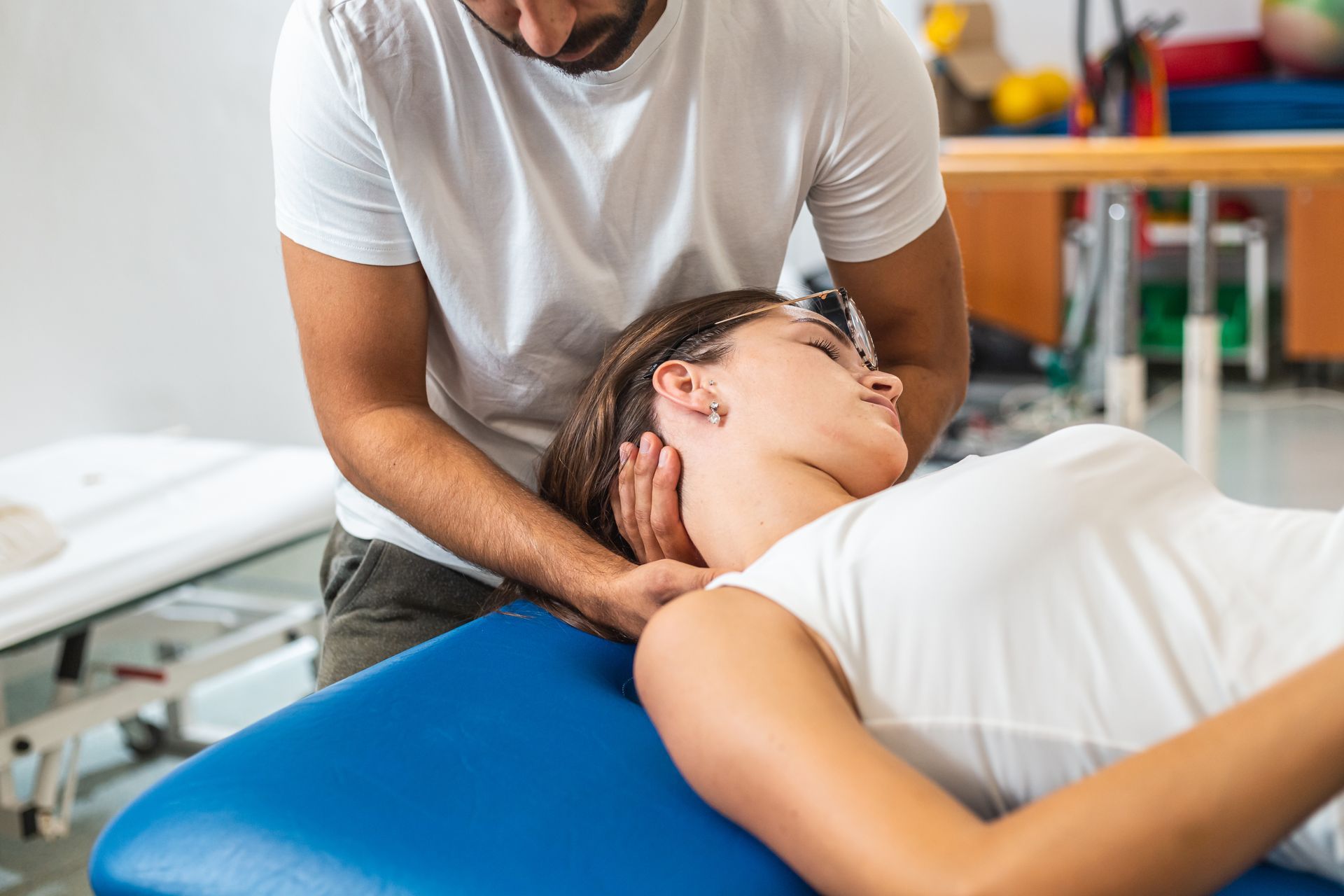 Chiropractor performing a manual neck adjustment on a patient lying on a treatment table.
