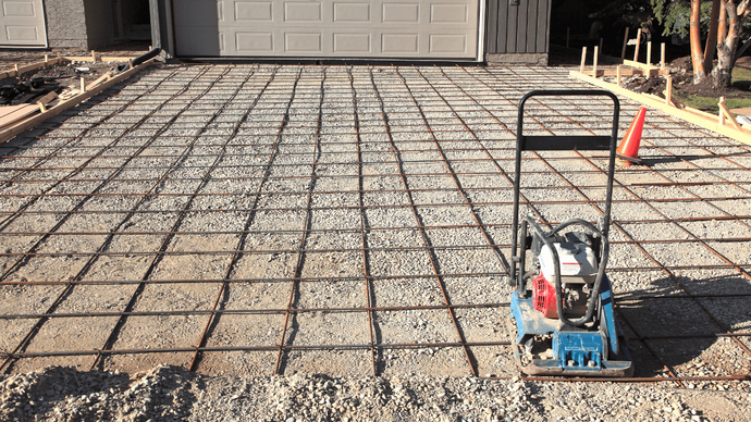 “Prepared driveway area with a full rebar grid and compactor ready for a new concrete pour during concrete services in Casas Adobes, AZ”