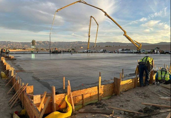 “Concrete pump hose reaching over wood forms while workers place a wide slab by a concrete contractor in Casas Adobes, AZ”