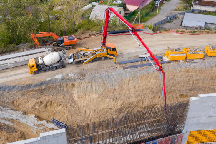 “Concrete pump truck extending across a construction site to pour material into a foundation area by a concrete contractor in Casas Adobes, AZ”