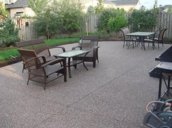 “Spacious backyard concrete patio with outdoor tables, chairs, and a shaded gathering area by a concrete contractor in Casas Adobes, AZ”