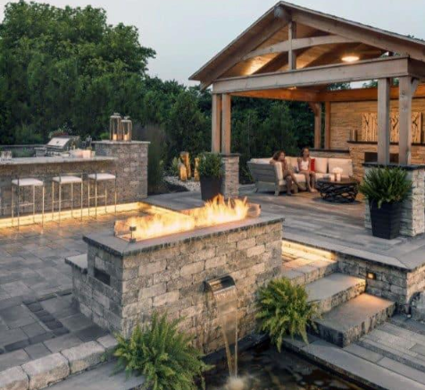 “Outdoor living area with concrete pavers, a fire feature, and covered seating by a concrete contractor in Casas Adobes, AZ”