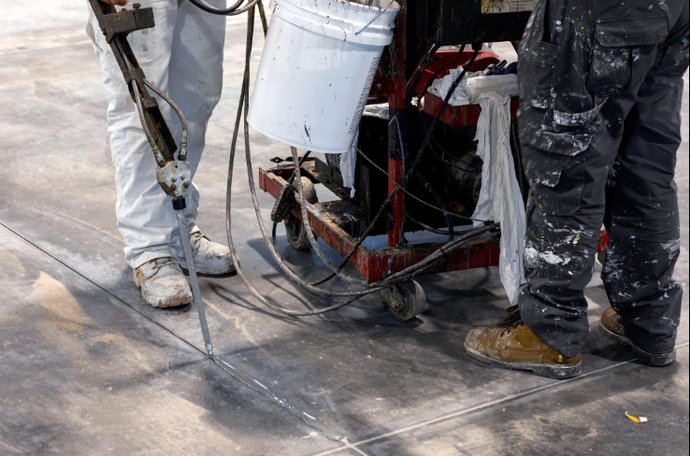“Worker using repair equipment to restore a damaged concrete surface by a concrete contractor in Casas Adobes, AZ”