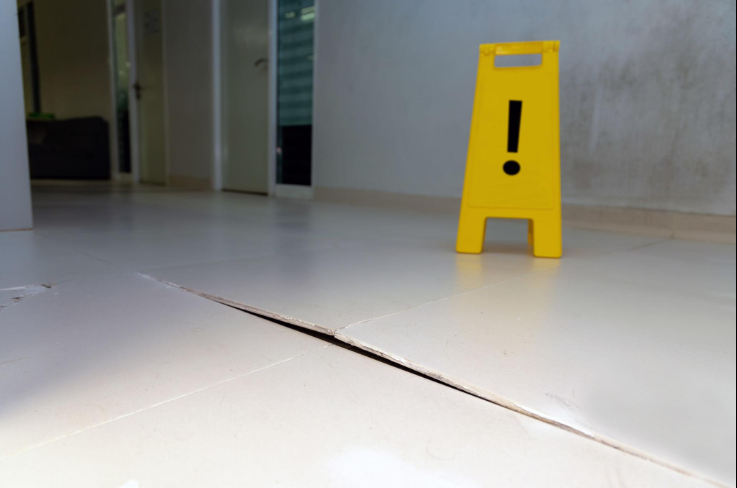 “Indoor concrete floor with a visible crack and safety sign during repair work by a concrete contractor in Casas Adobes, AZ”