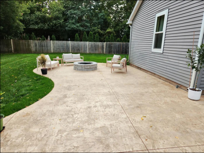 “Stamped concrete patio with outdoor chairs, a fire feature, and backyard landscaping by a concrete contractor in Casas Adobes, AZ”