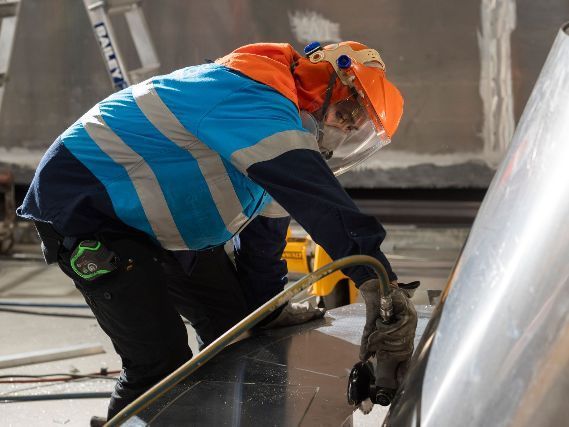 A man wearing a helmet is working on a piece of metal