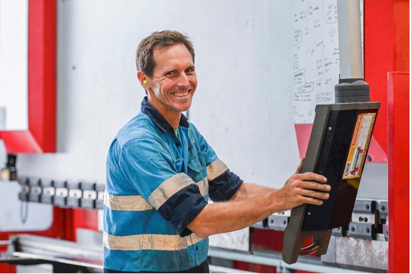 A man is standing in front of a machine and smiling.