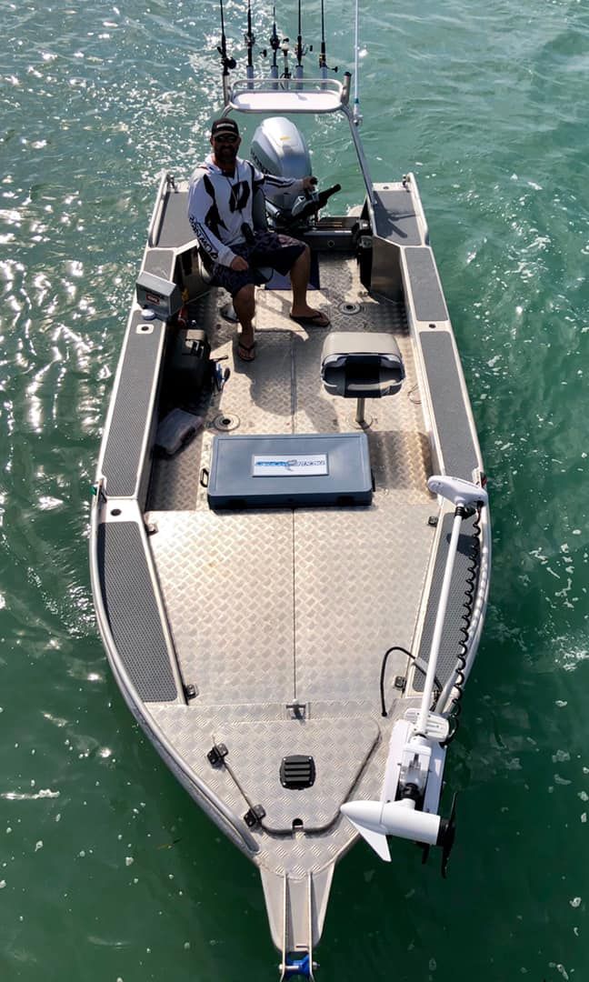 A man is sitting on the front of a boat in the water.