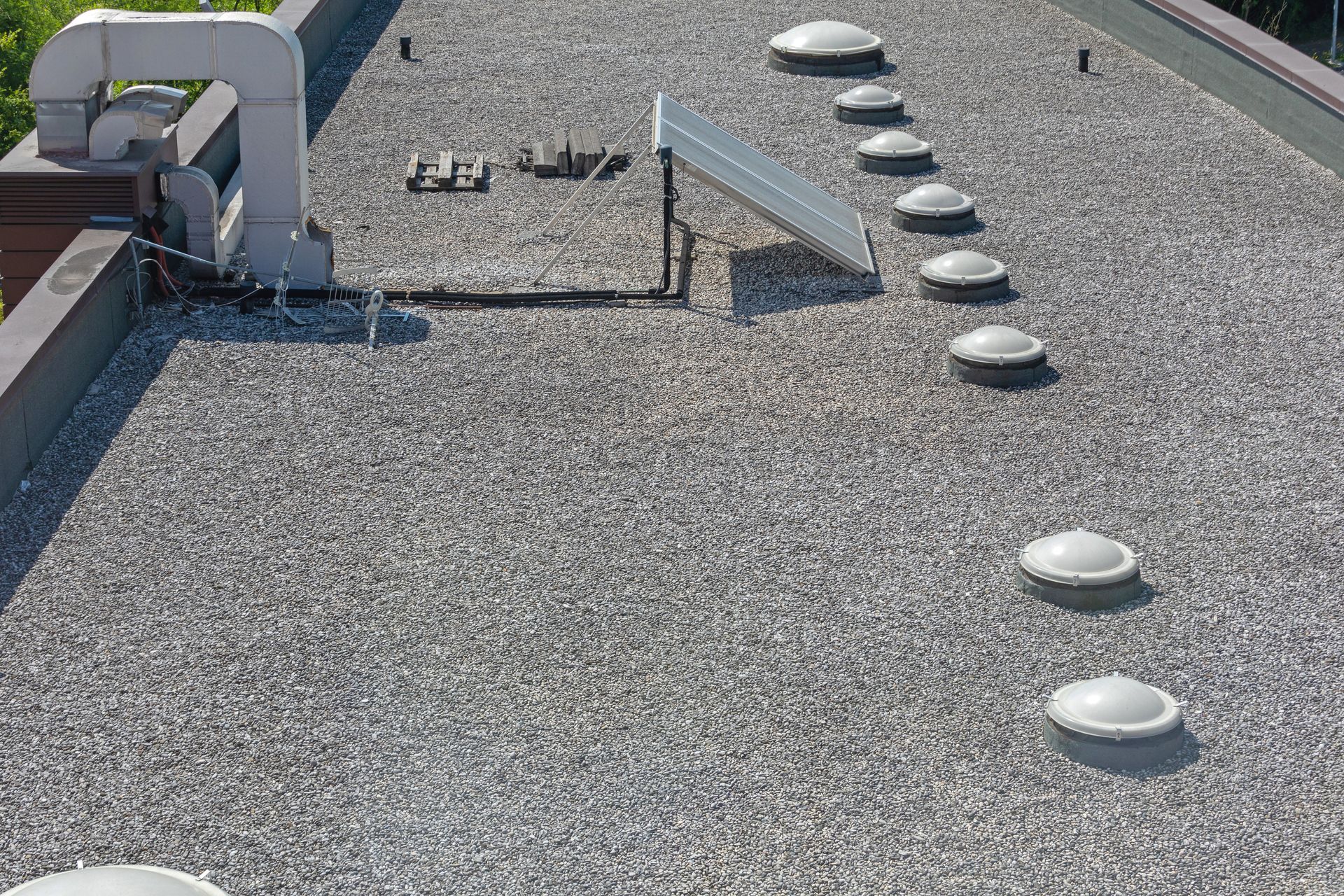 Rooftop with gravel surface, ventilation pipes, and a row of circular roof vents.