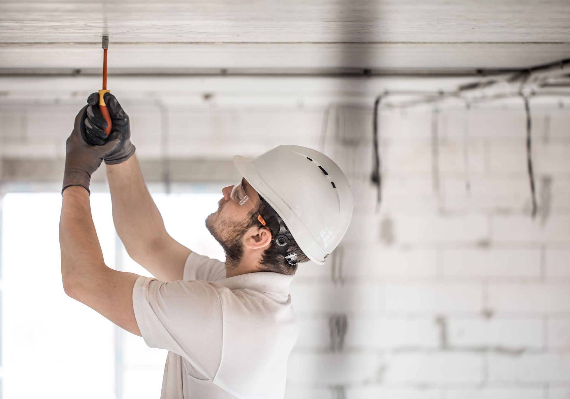 A man is measuring a ceiling with a tape measure.