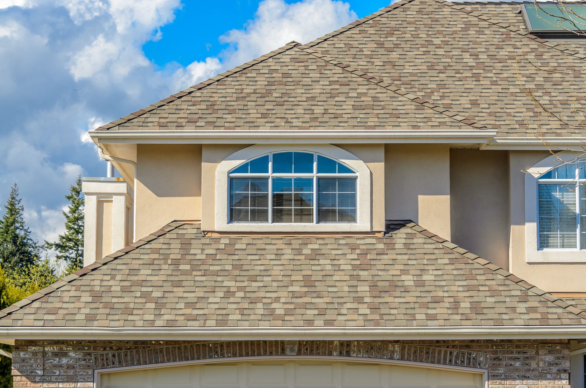 A large house with a shingle roof and a large window.