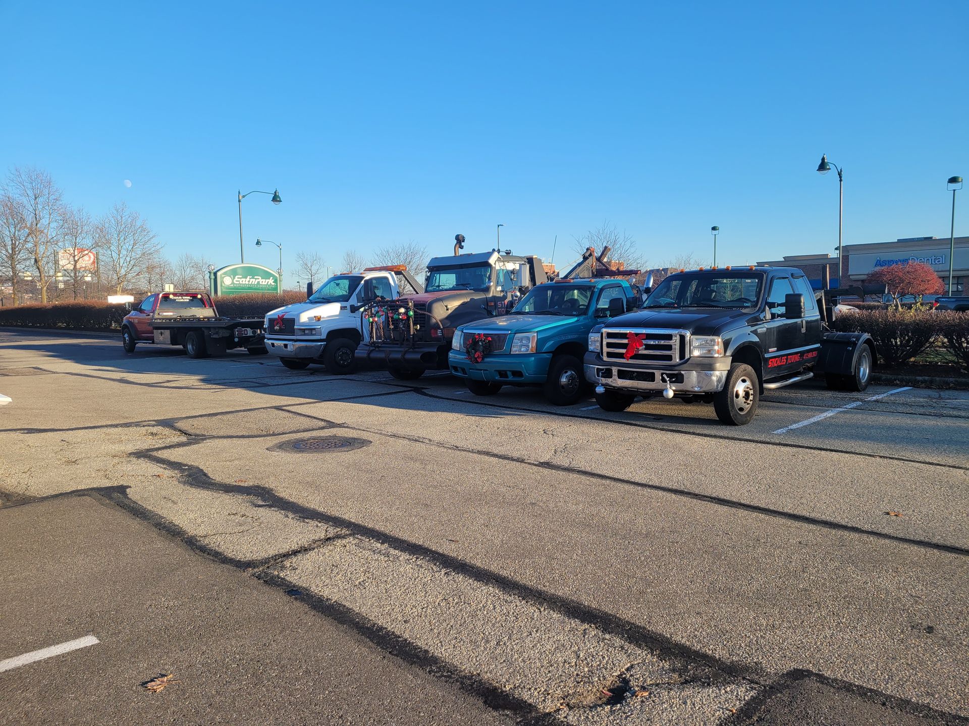 A row of tow trucks are parked in a parking lot.