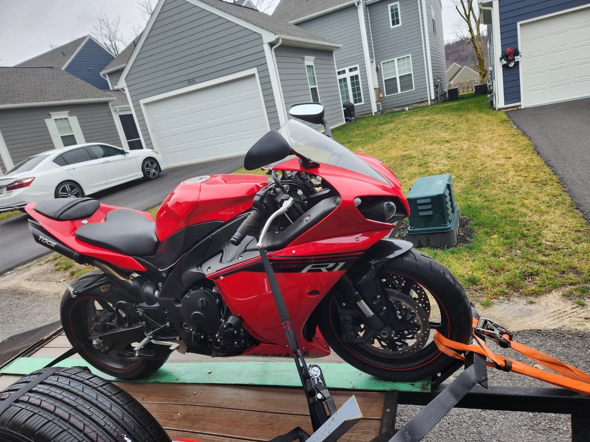 A red motorcycle is on a trailer in front of a house.