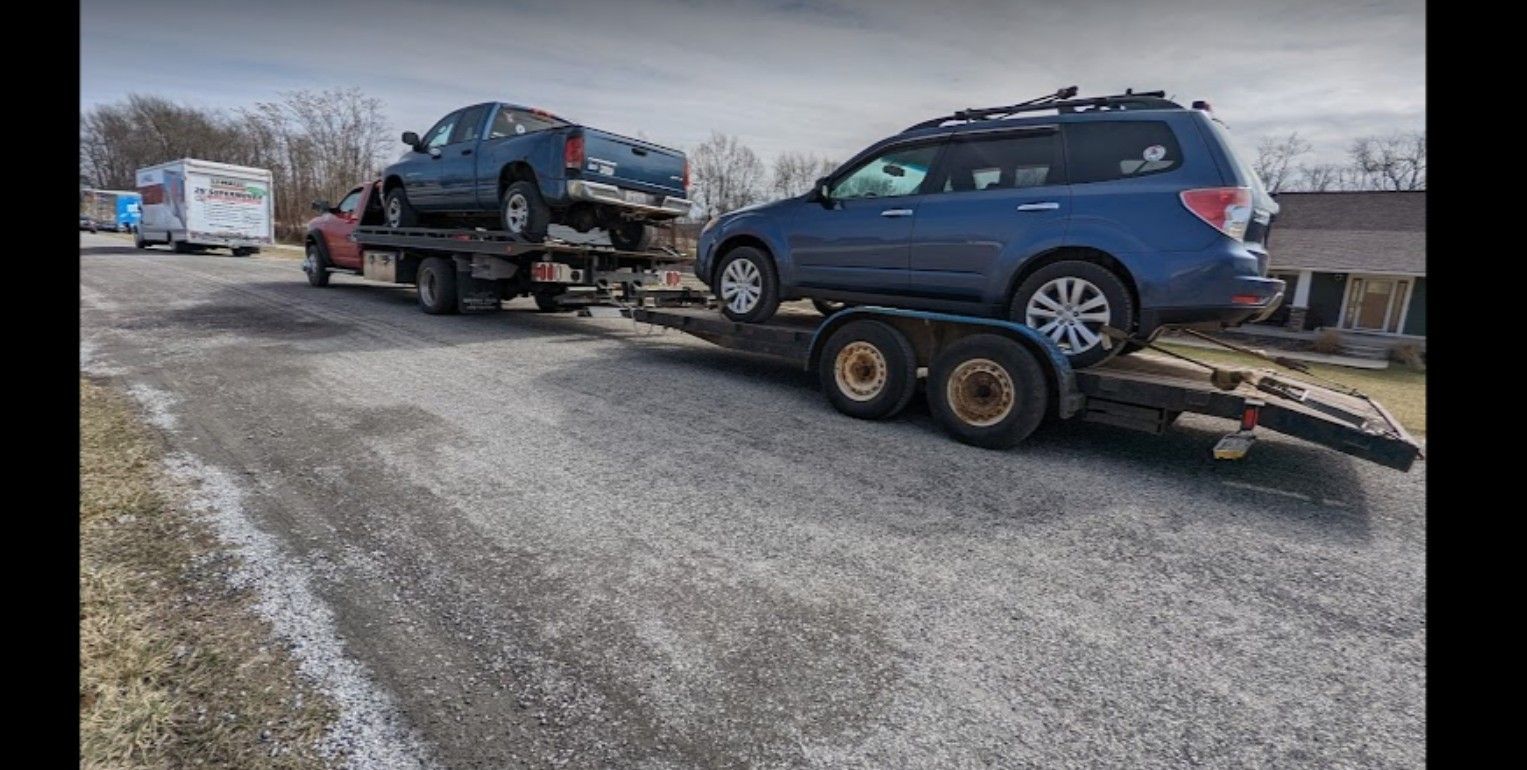 A tow truck is towing a blue suv on a trailer.