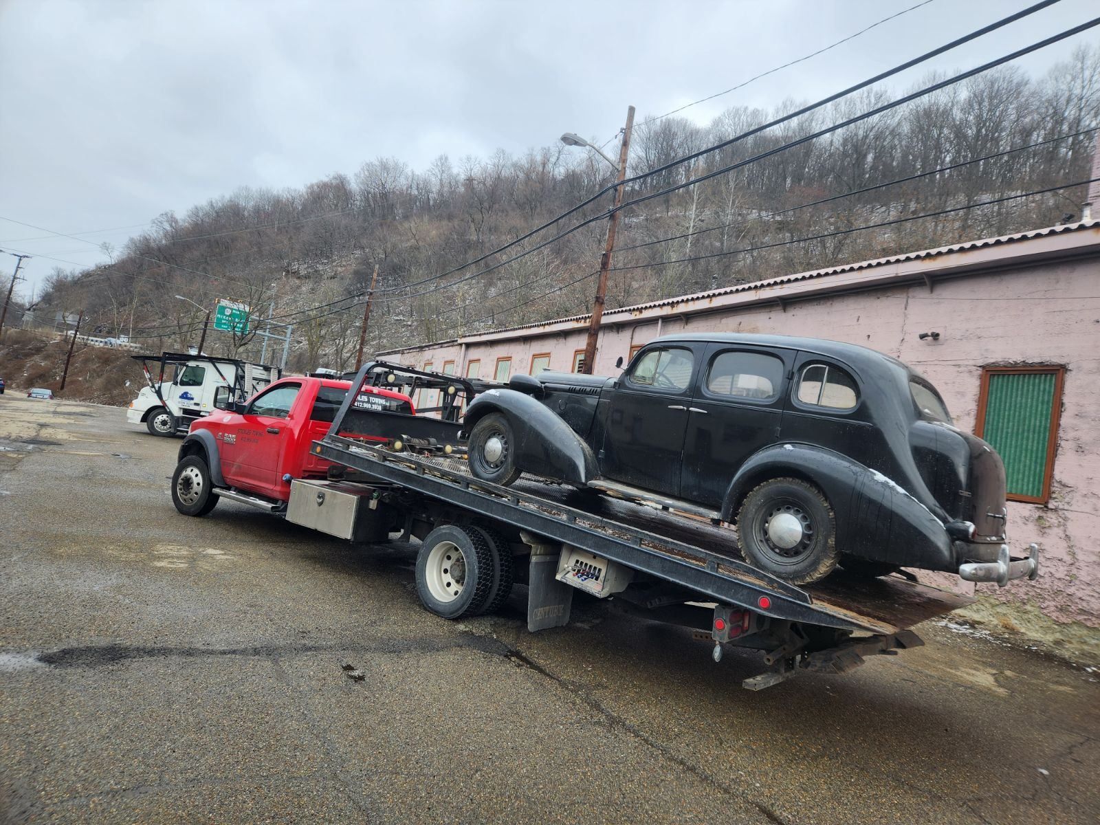 An old car is being towed by a tow truck.