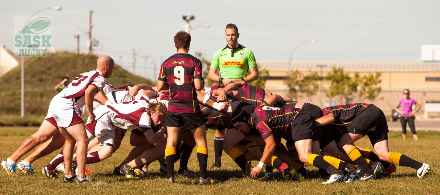 Two rugby teams in a scrum on a field, supervised by a referee in a bright green shirt.