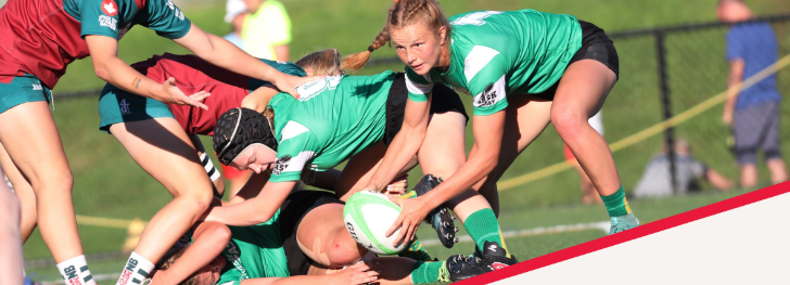 Rugby players in green and red jerseys engage in a scrum on a green field.