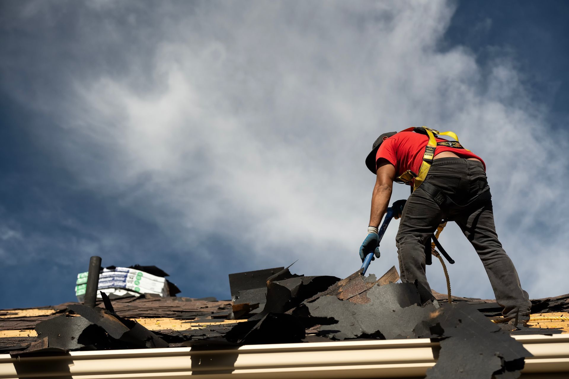 Roofing contractor removing old, damaged shingles from a home during a roof replacement inspection