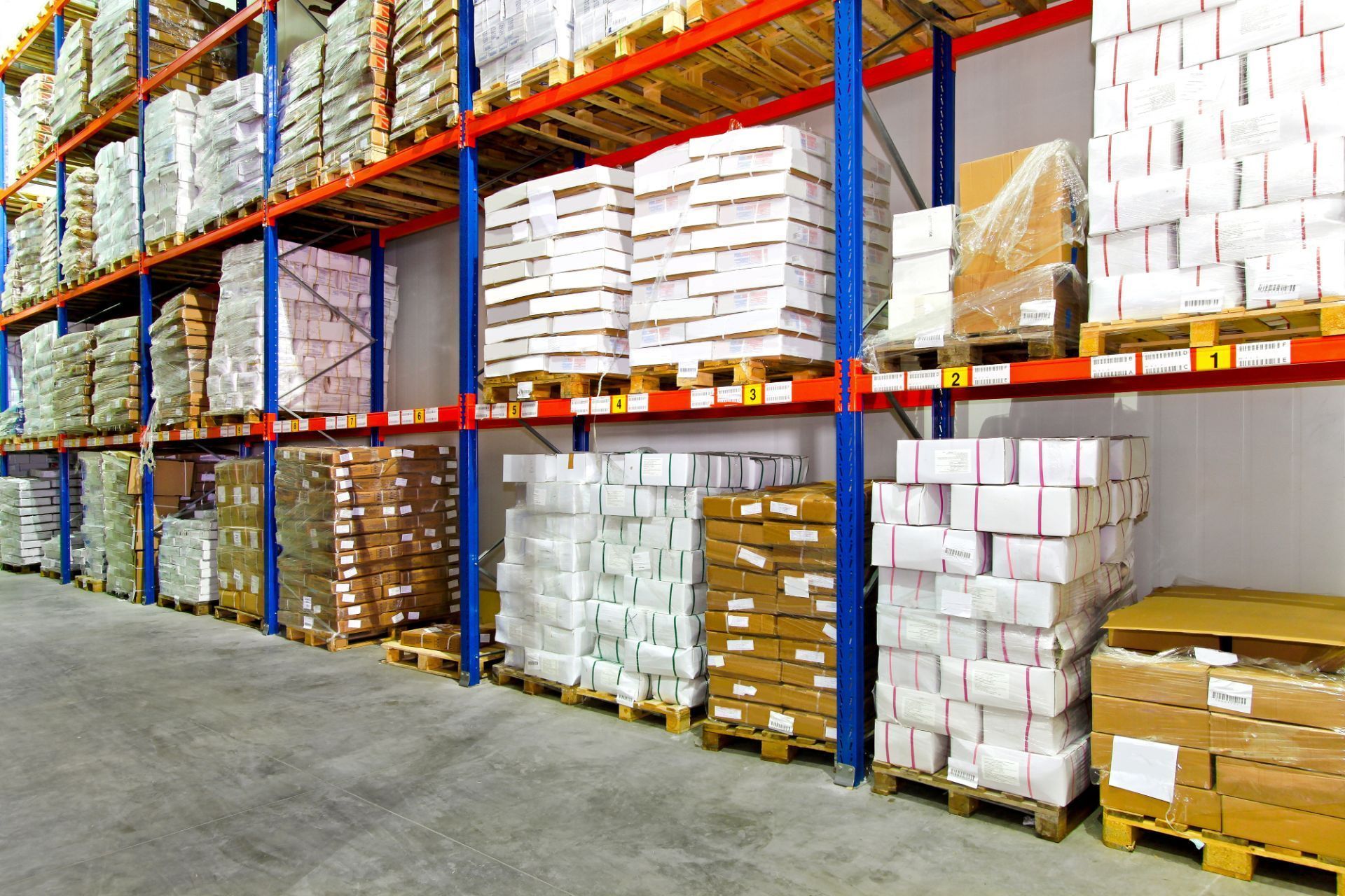 Scaffali del magazzino pieni di scatole e pallet avvolti, vista interna.
