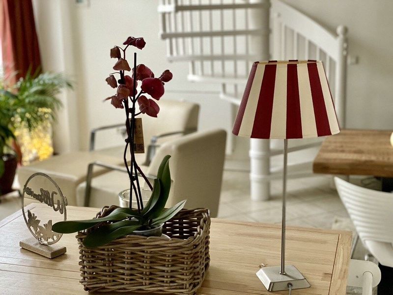 Eine Lampe mit rot-weiß gestreiftem Schirm steht auf einem Tisch neben einem Blumenkorb.