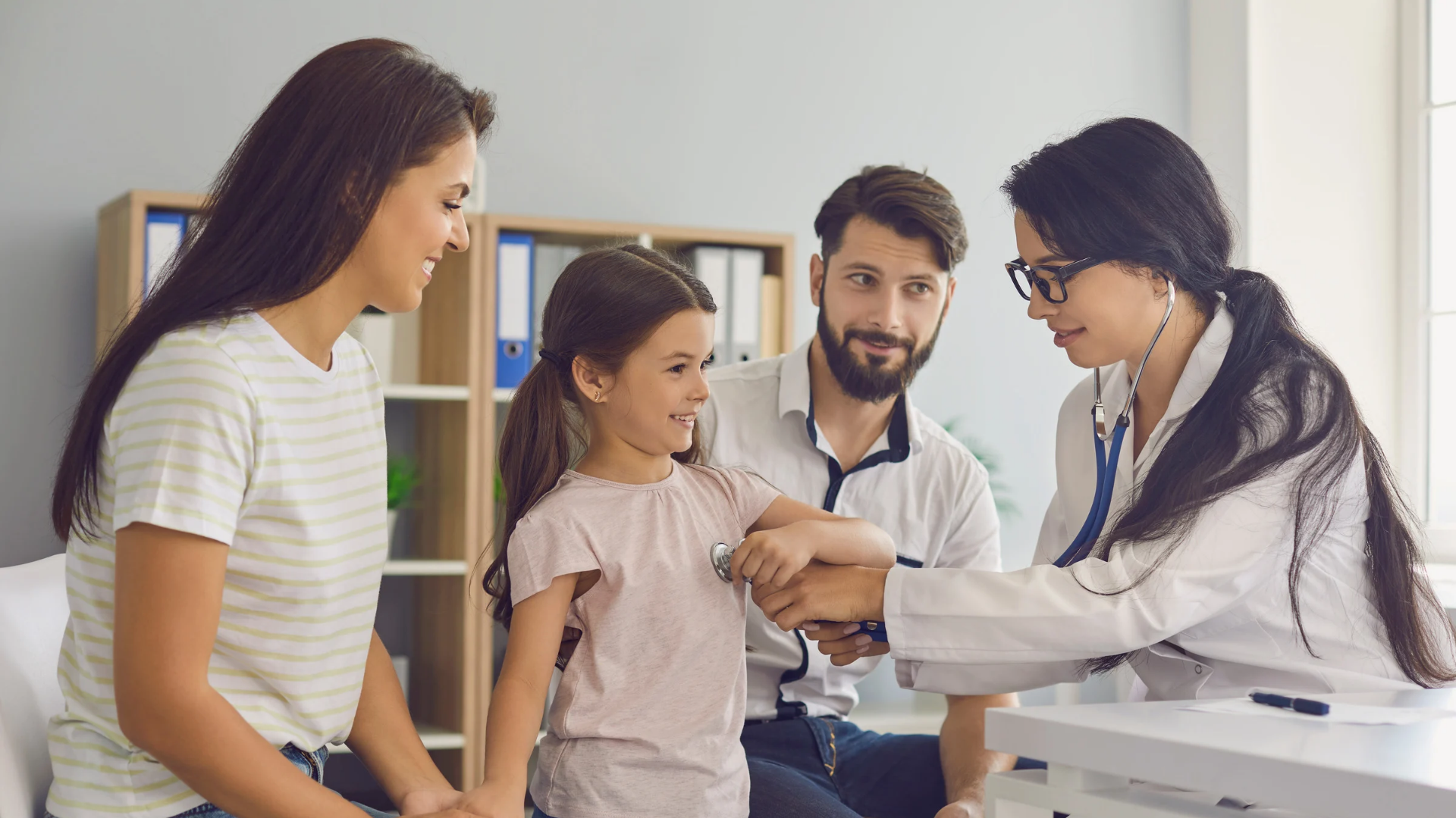 DPC practicioner examining a child with parents in a clinic office