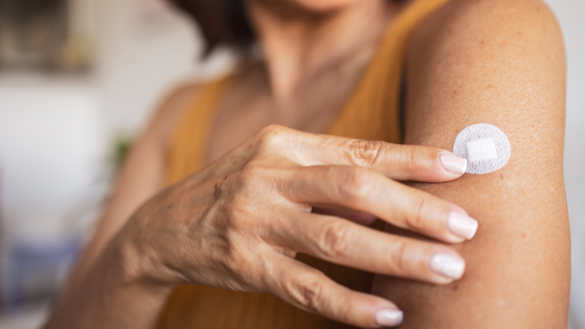 Person applying sunscreen to their upper arm with a small round applicator applicator