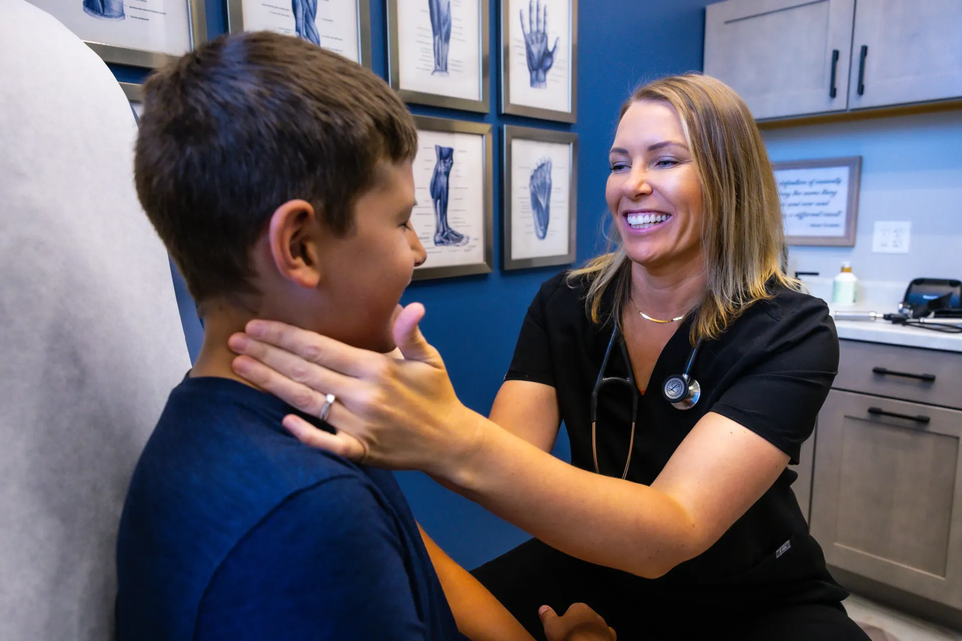 Health professional smiling and examining a child’s neck in a clinic room