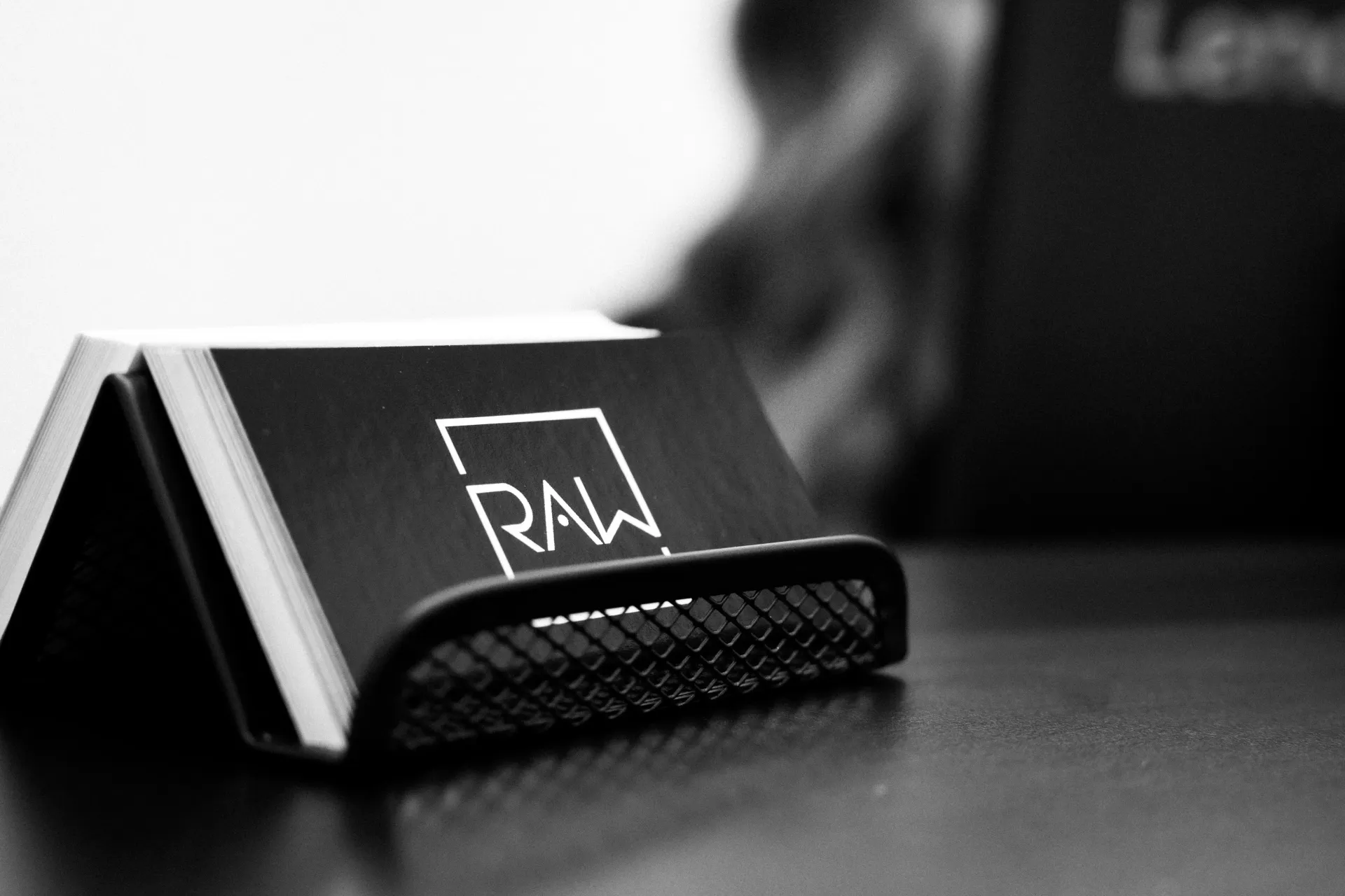 Black-and-white close-up of a small RAW rolling paper pack on a table