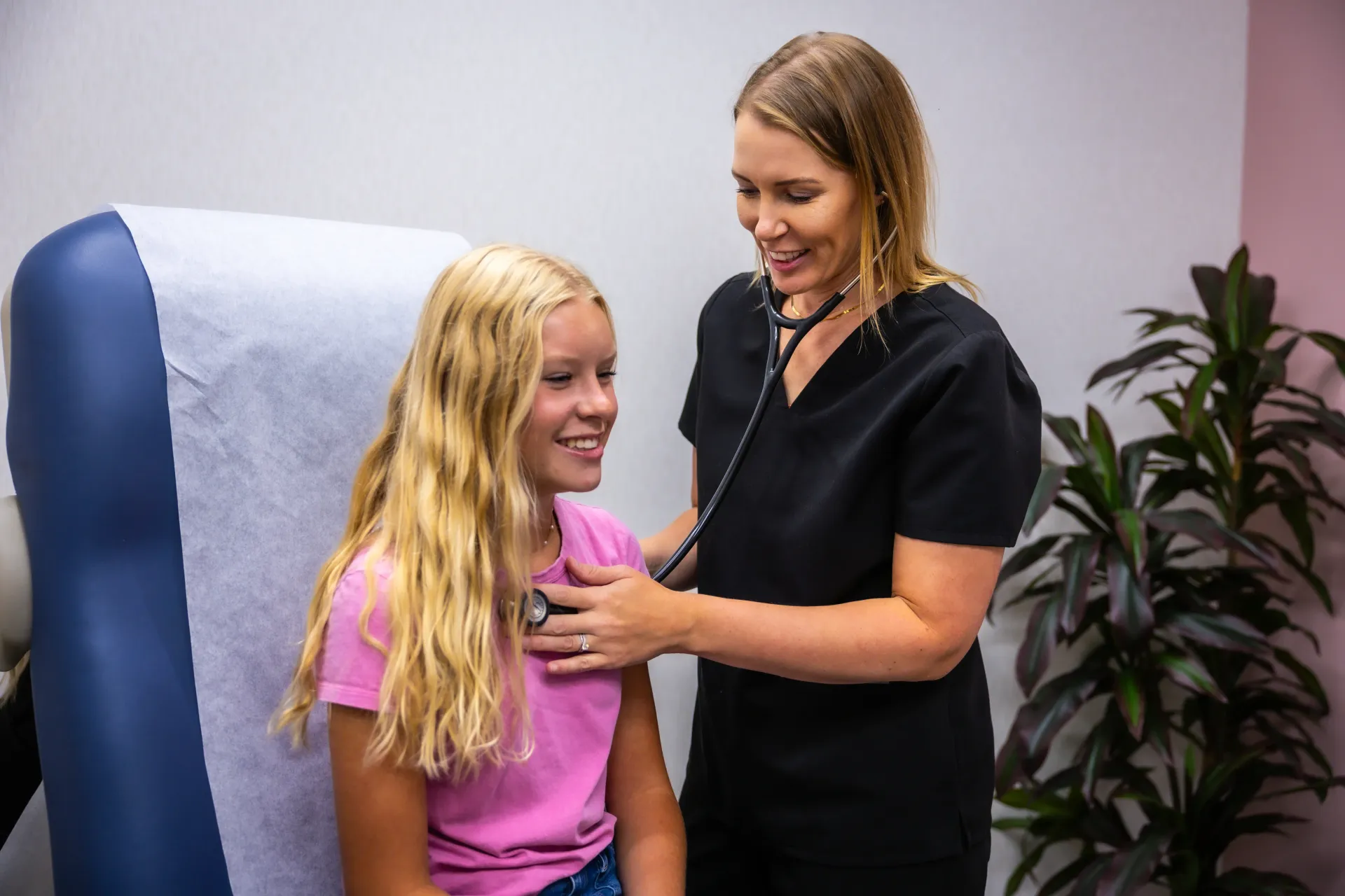 Patient smiling while clinician checks her shoulder in a medical exam room