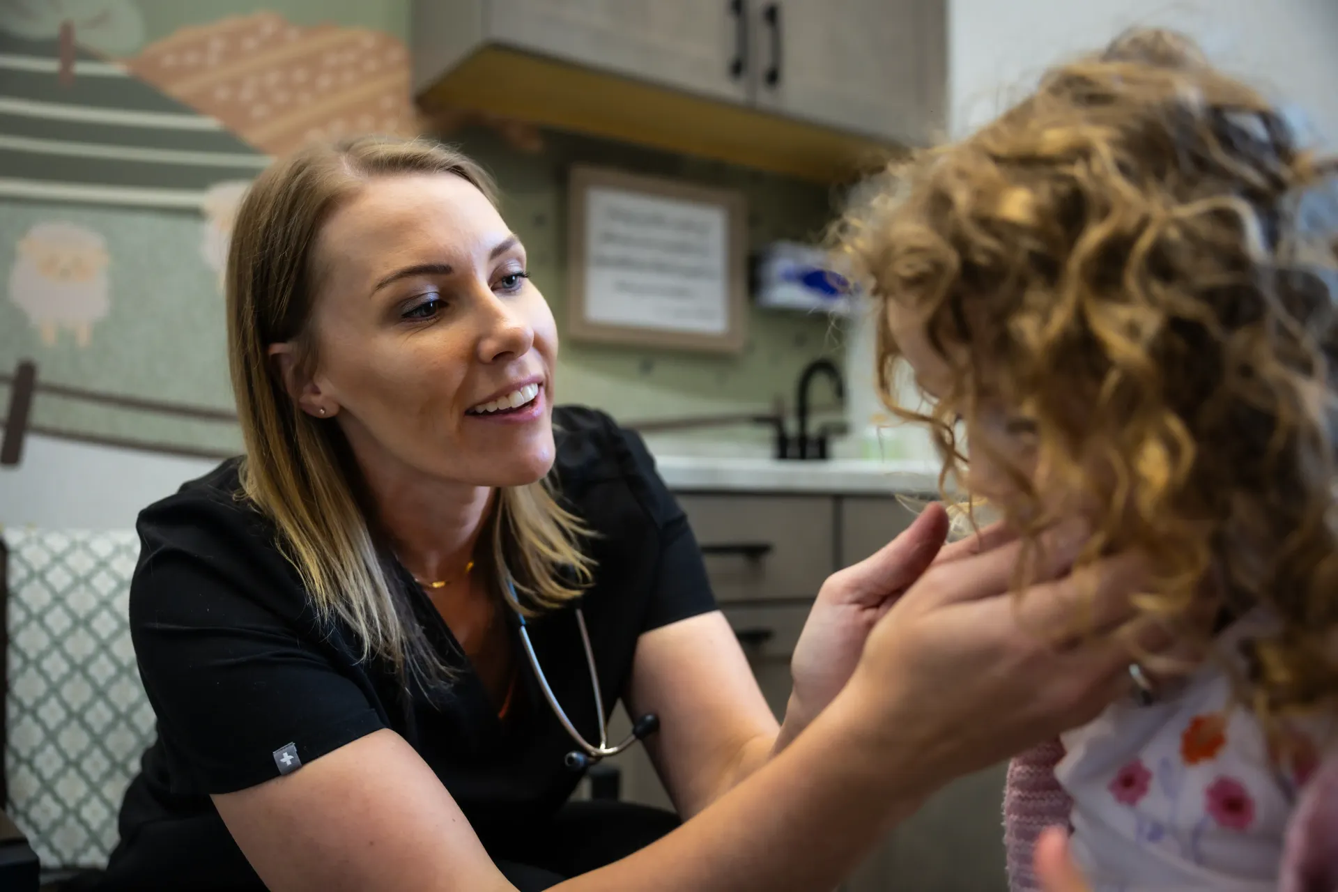 Woman gently touching a child’s face in a classroom, both smiling during a conversation
