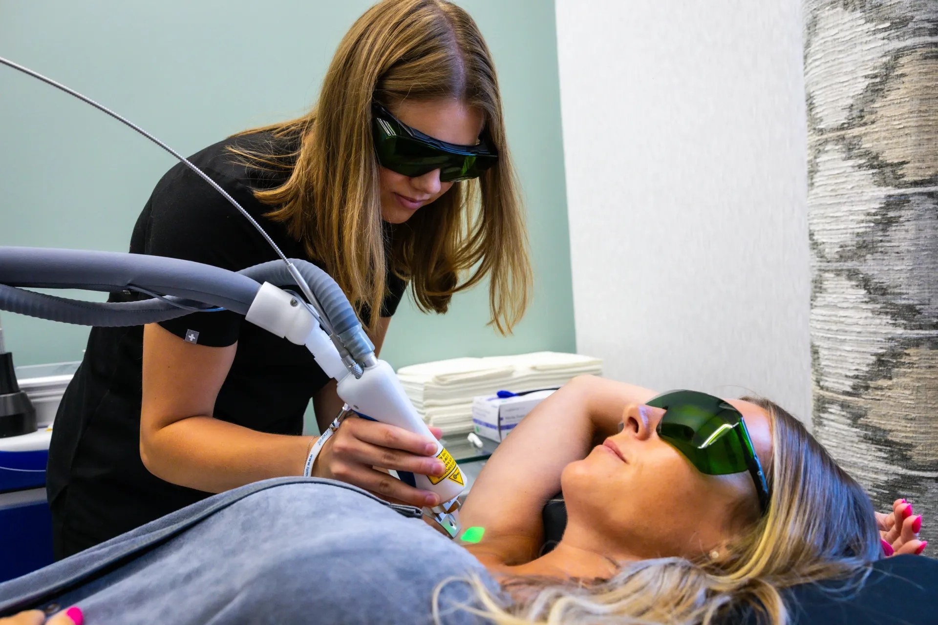 Dentist using a handheld laser on a patient wearing protective glasses during a dental treatment