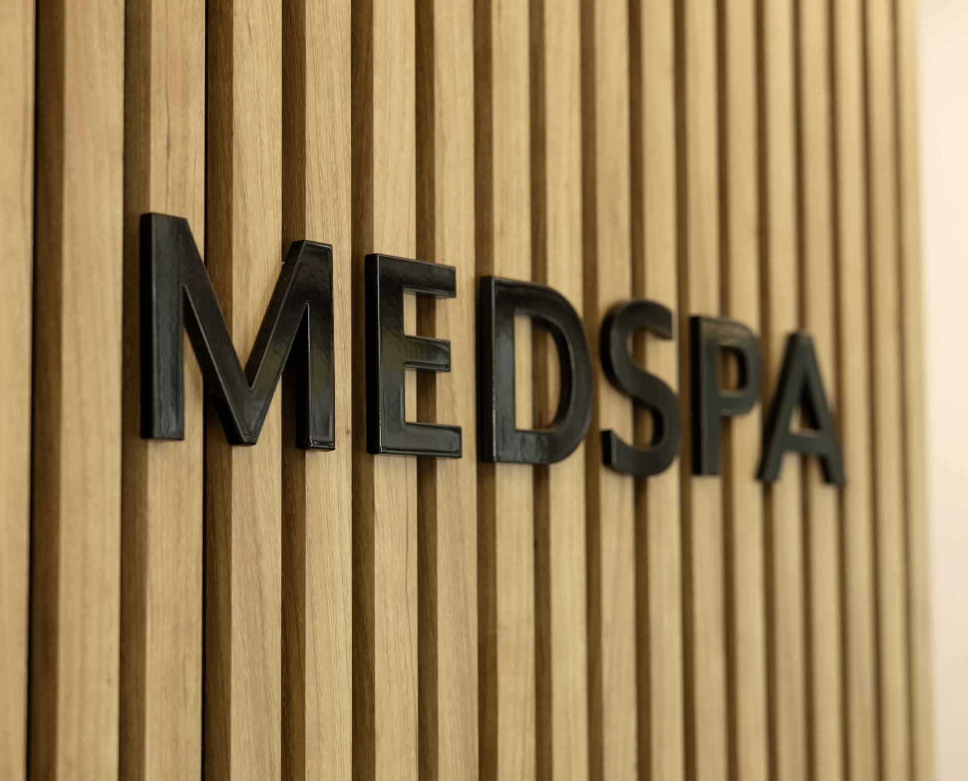 MEDSPA sign in black letters on a vertical wood-slat wall