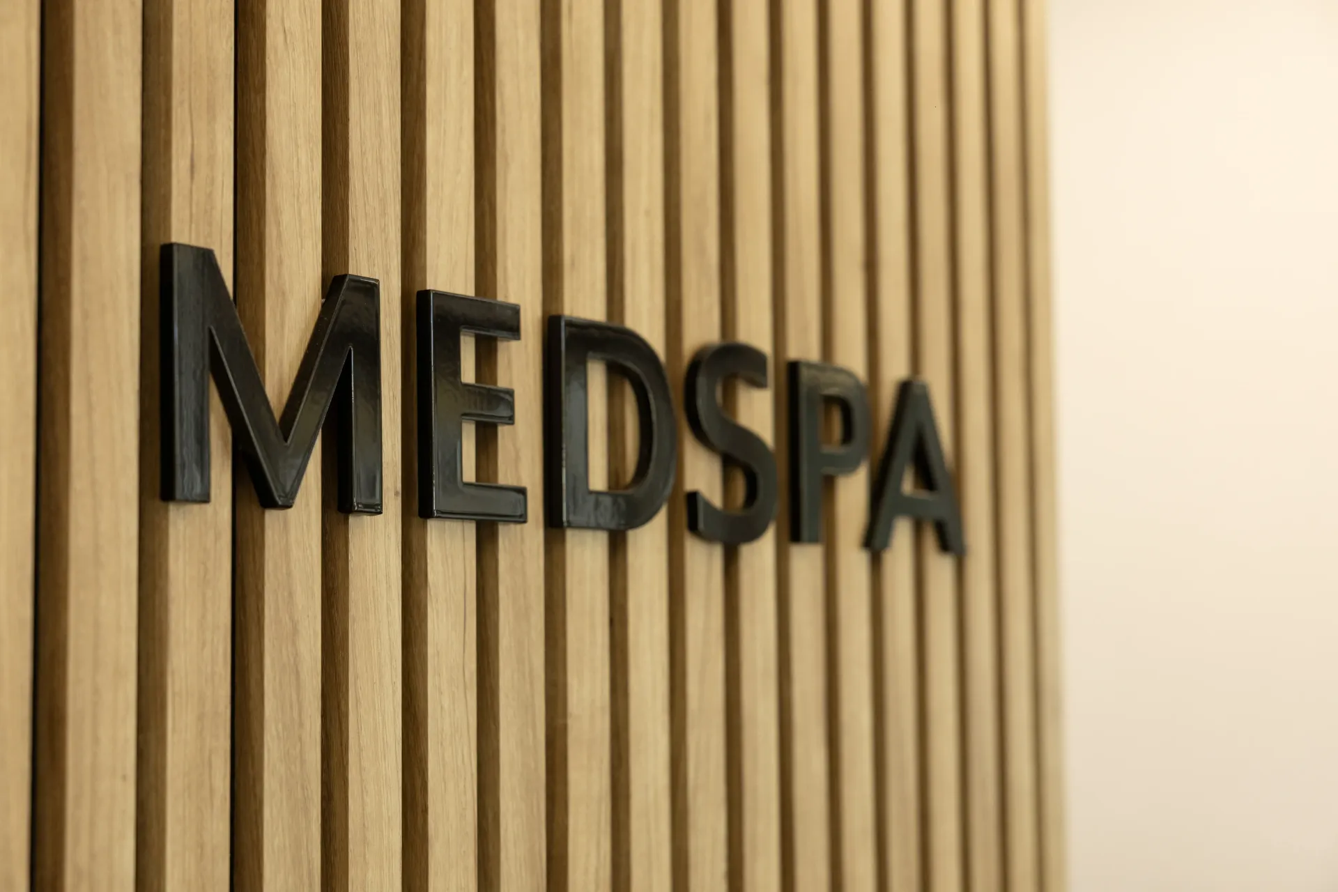 Black MEDSPA sign on a light wood slat wall