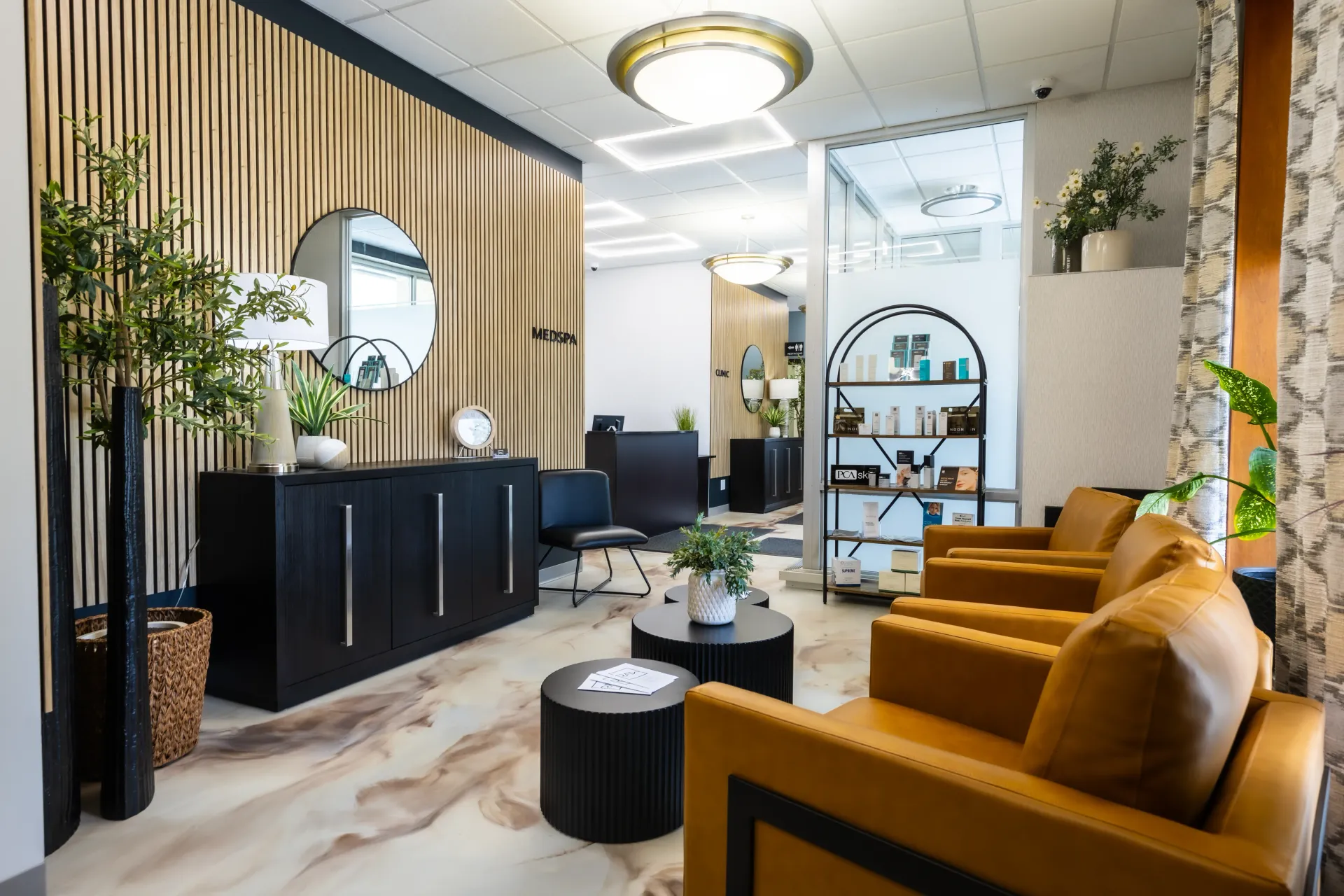 Modern salon interior with mustard chairs, black reception desk, striped walls, and decorative plants