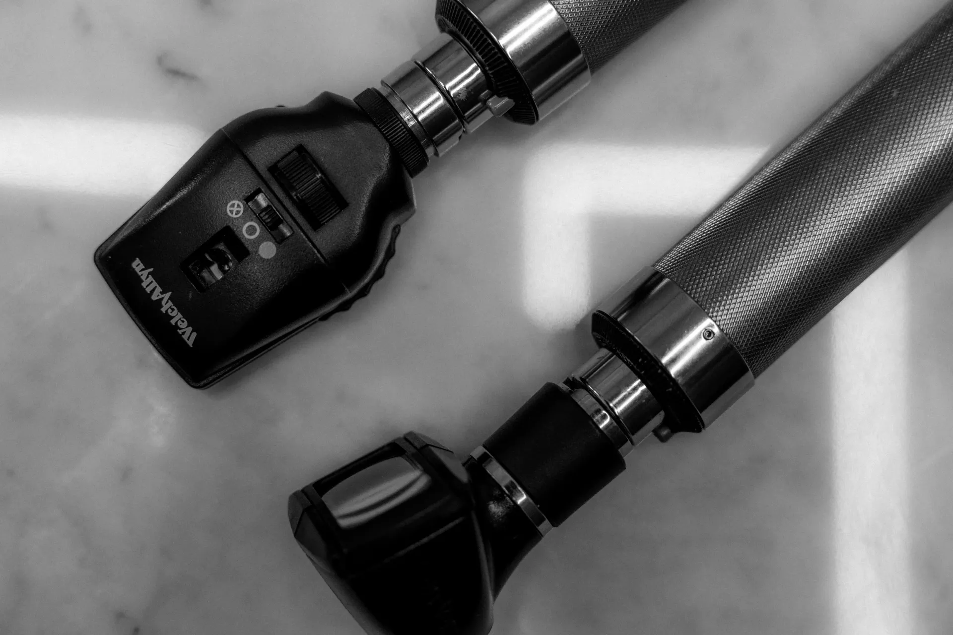 Close-up of two black handheld devices with textured grips on a light surface