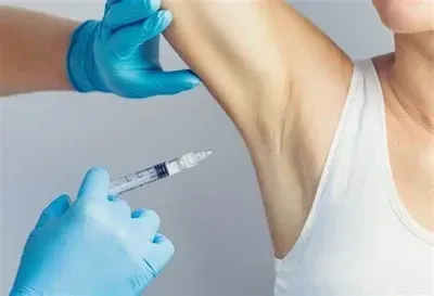 Gloved hands giving an injection to an upper arm